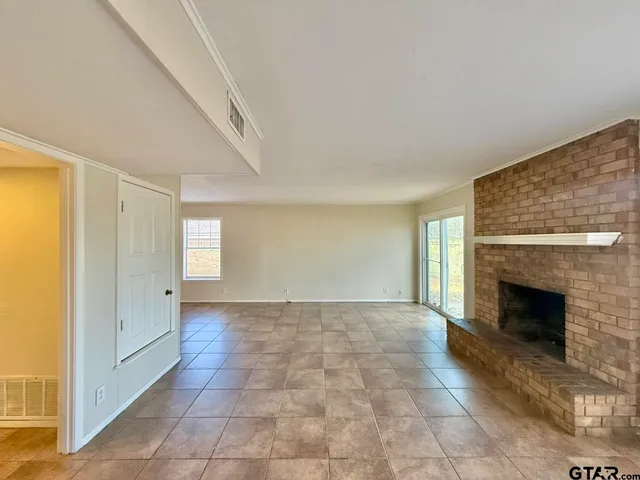 an empty room with windows and fireplace