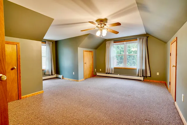 an empty room with windows and fan
