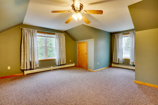 a view of an empty room with window and chandelier fan
