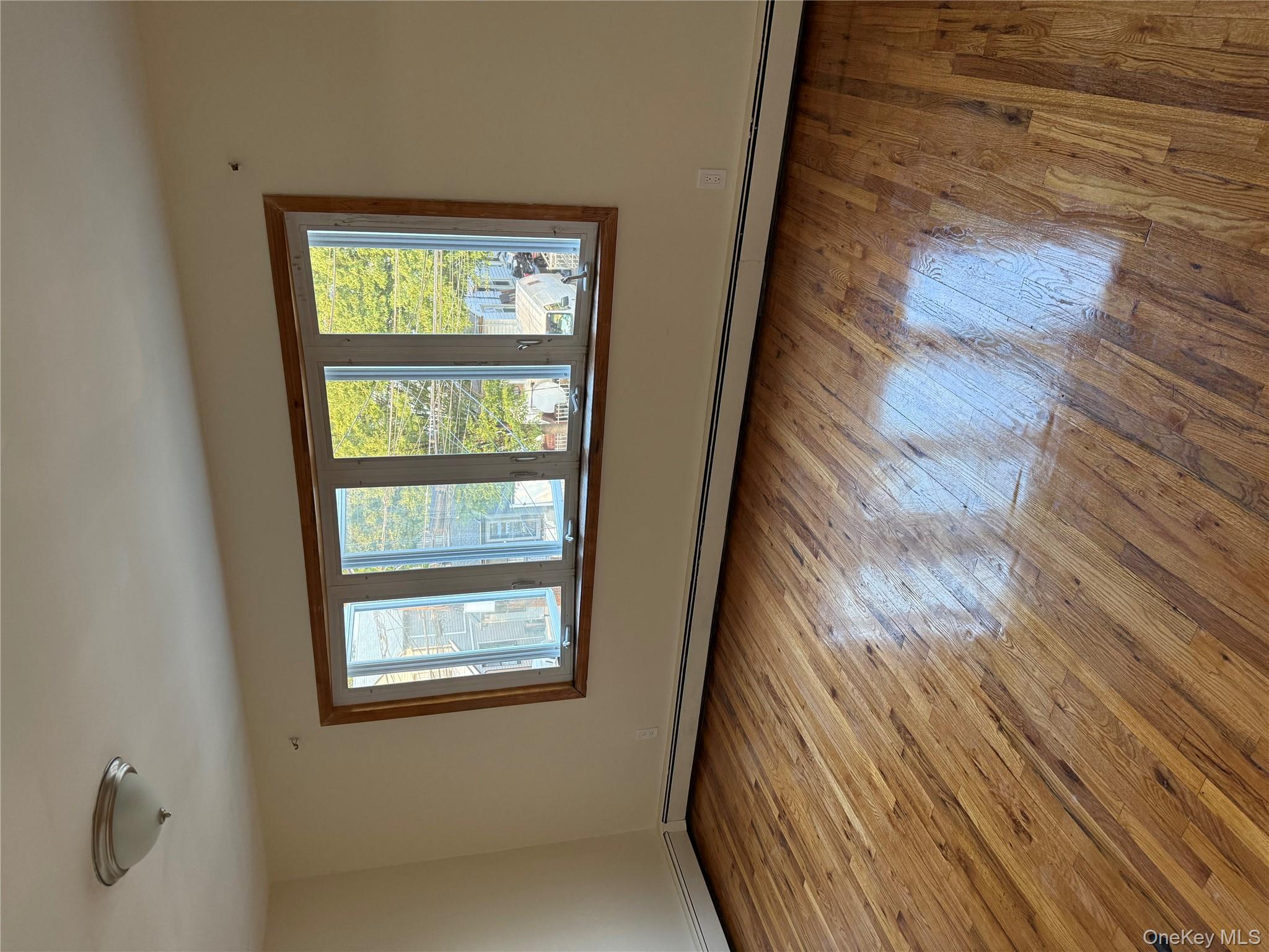 102-12 216th Street Queens, NY 11429 - Photo 2 of 10 a view of an empty room with wooden floor and a window