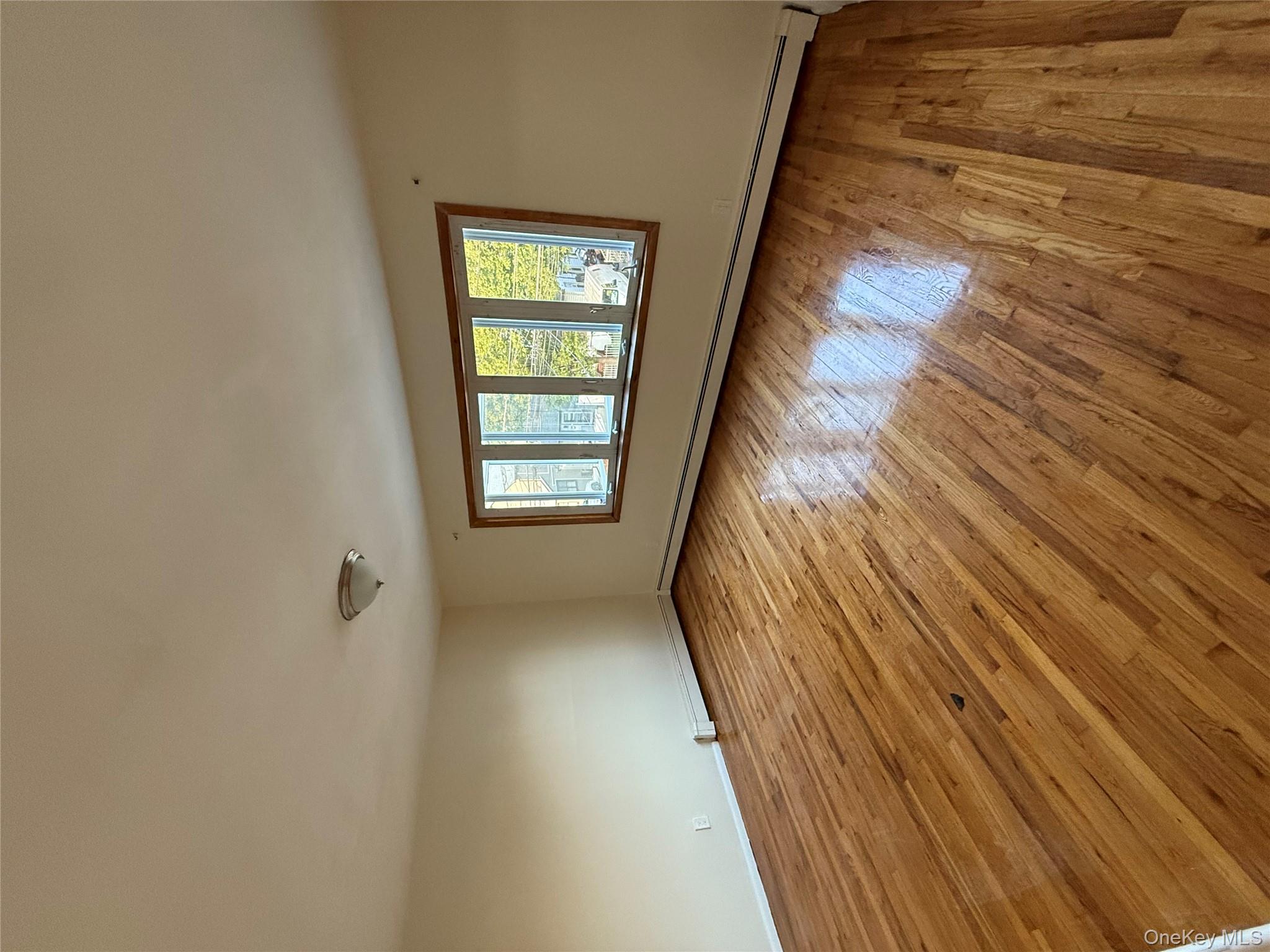 102-12 216th Street Queens, NY 11429 - Photo 3 of 10 a view of empty room with wooden floor and fan