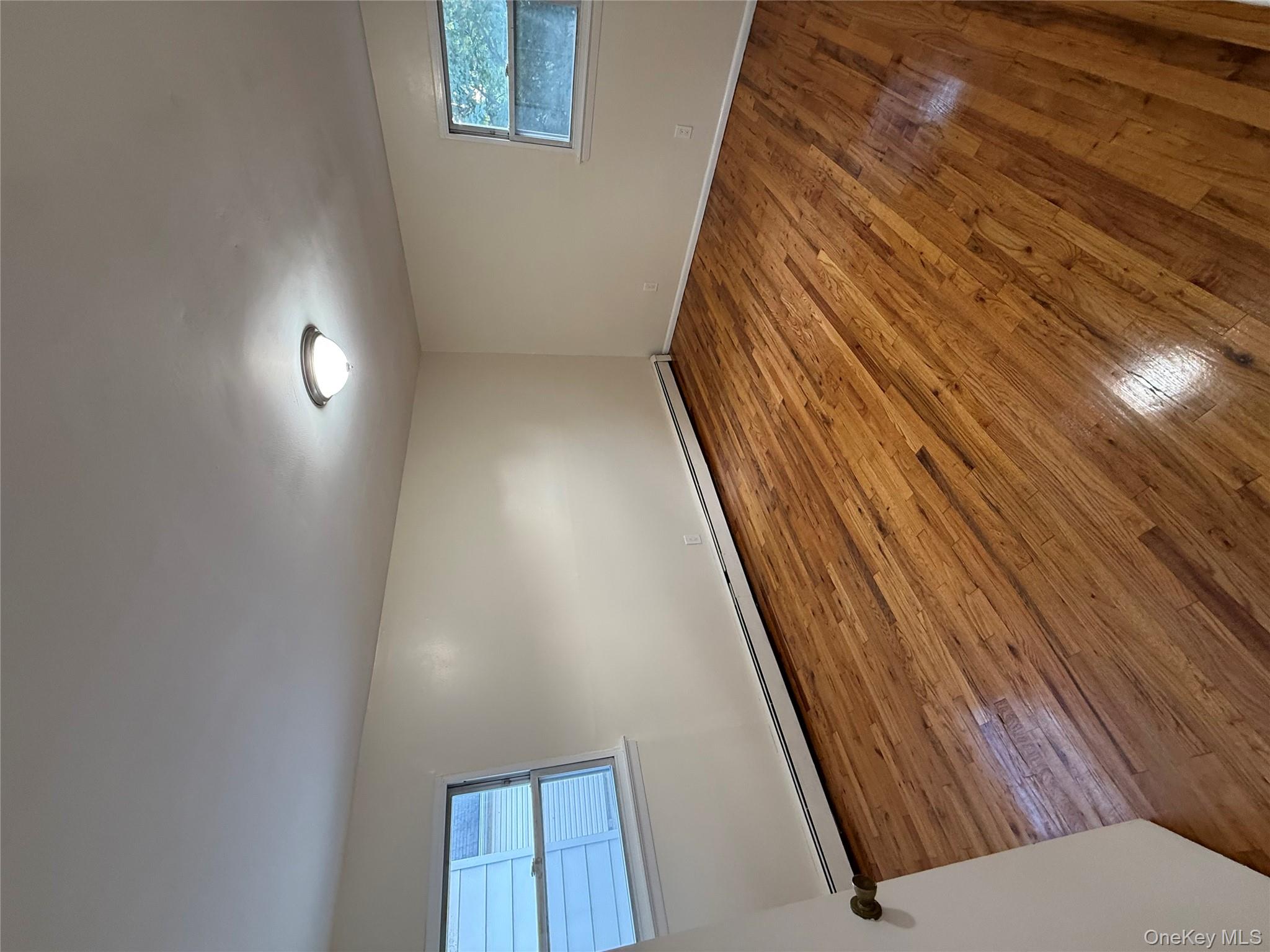 102-12 216th Street Queens, NY 11429 - Photo 7 of 10 an empty room with wooden floor and windows