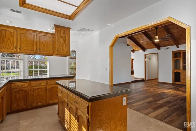 a view of an empty room with a window and kitchen view