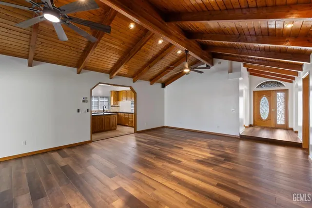 a view of an empty room with wooden floor and a fireplace