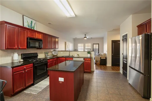 a kitchen with stainless steel appliances granite countertop a refrigerator a stove a sink a microwave and a refrigerator