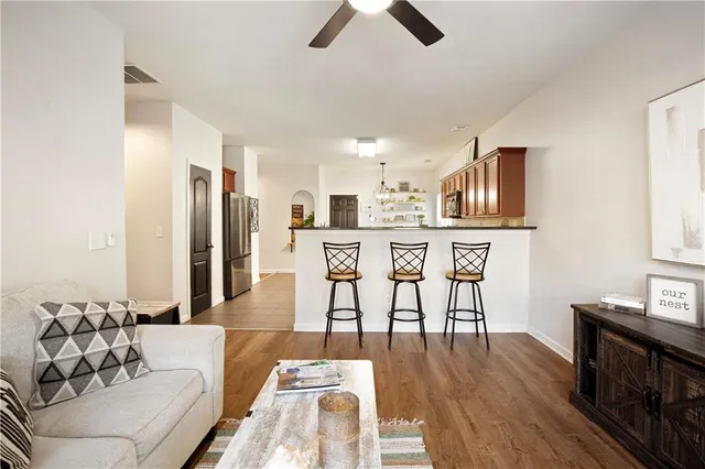 a living room with stainless steel appliances kitchen island granite countertop furniture and a wooden floor