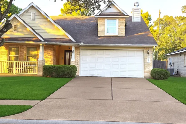 a view of a white house with a small yard and a large tree
