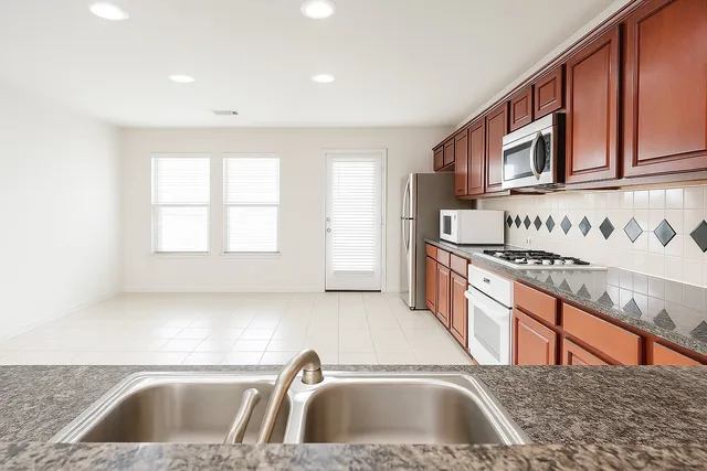 a kitchen with stainless steel appliances granite countertop a sink and a stove top oven