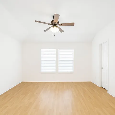 an empty room with a window and a ceiling fan