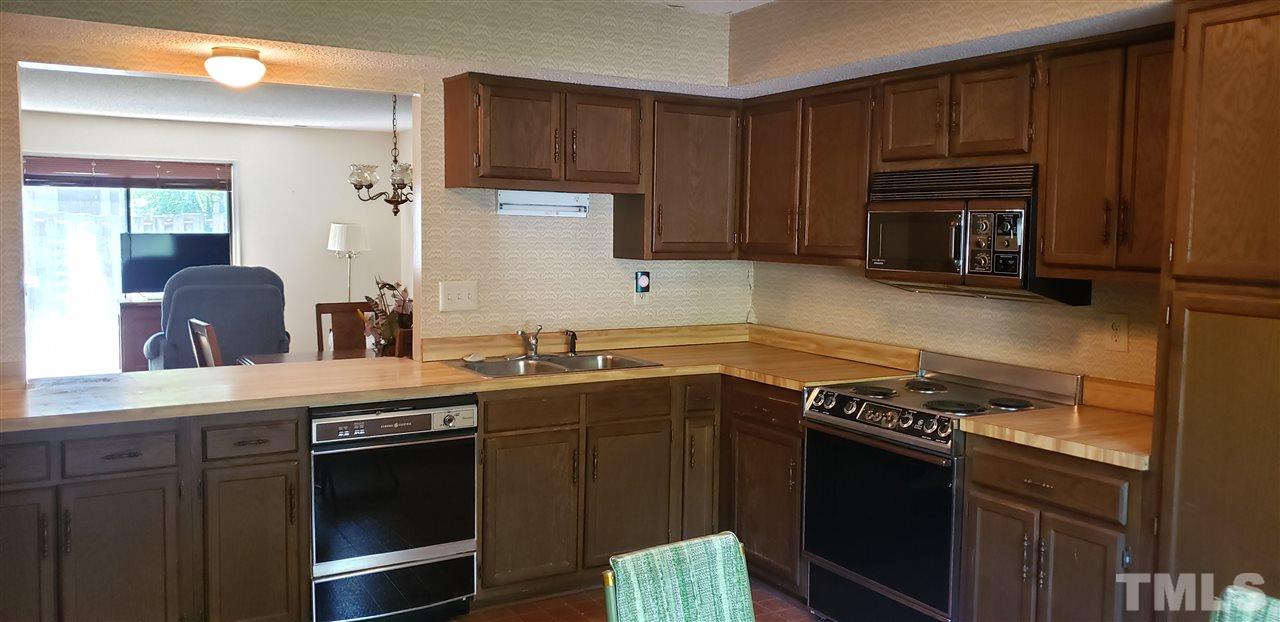1227 Seaton Road, Unit 55 Durham, NC 27713 - Photo 5 of 6 a kitchen with wooden cabinets and a stove top oven