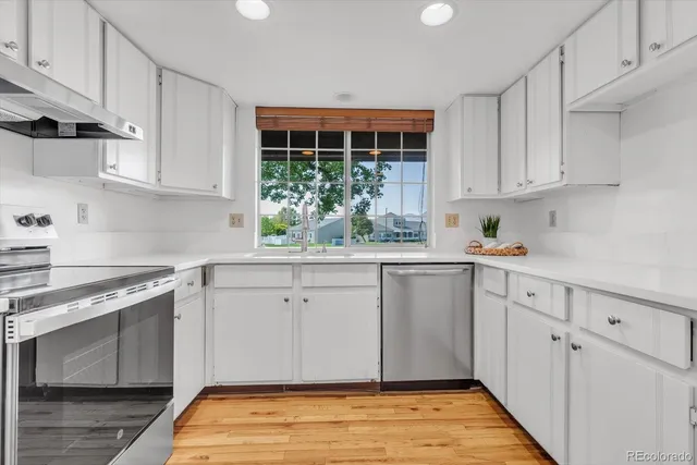 a kitchen with stainless steel appliances granite countertop a stove a sink and white cabinets