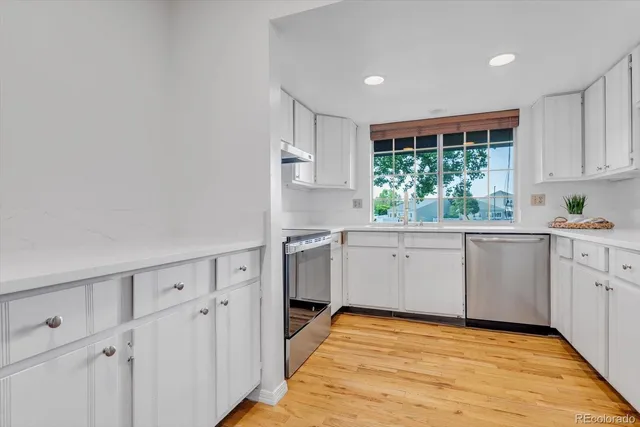 a kitchen with white cabinets and window