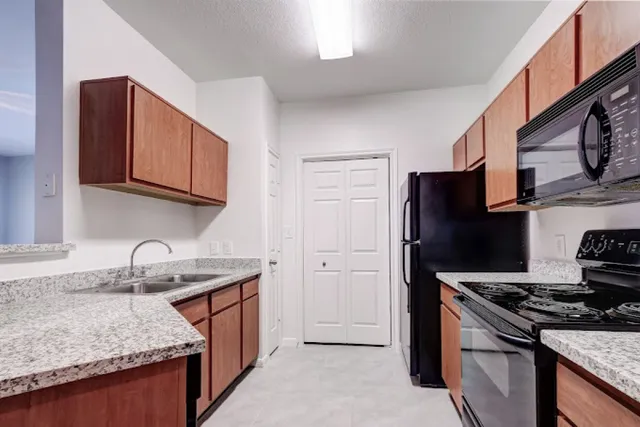 a kitchen that has a sink wooden cabinets and stainless steel appliances