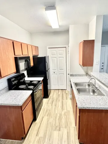 a kitchen with a sink stove top oven and refrigerator