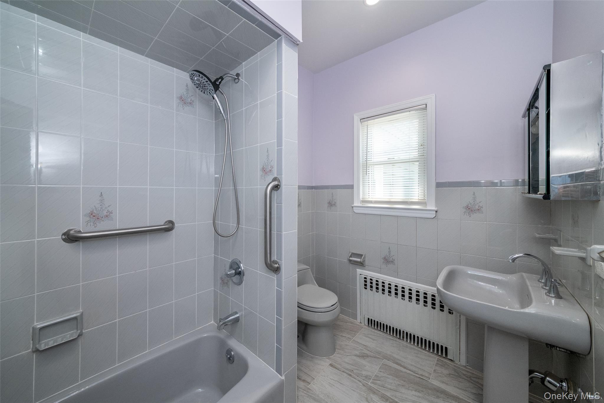 7 Alpha Place, Unit FIRST New Rochelle, NY 10805 - Photo 21 of 25 Bathroom with radiator, shower combination, tile walls