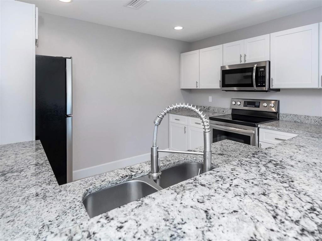 125 Boundary Boulevard, Unit 2 Rotonda West, FL 33947 - Photo 18 of 32 a kitchen with granite countertop a sink and a stove top oven
