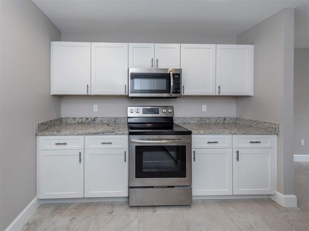 125 Boundary Boulevard, Unit 2 Rotonda West, FL 33947 - Photo 21 of 32 a kitchen with granite countertop white cabinets and stainless steel appliances