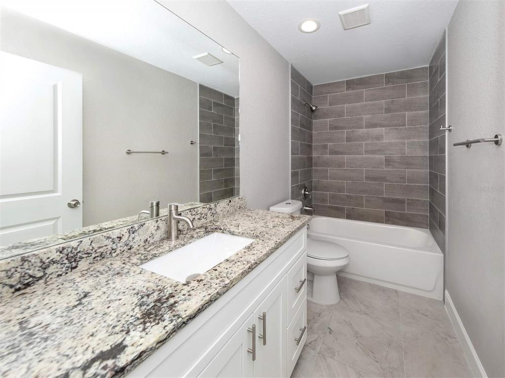 125 Boundary Boulevard, Unit 2 Rotonda West, FL 33947 - Photo 6 of 32 a bathroom with a granite countertop sink a toilet and bathtub