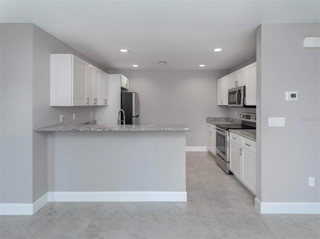 125 Boundary Boulevard, Unit 2 Rotonda West, FL 33947 - Photo 7 of 32 a kitchen with stainless steel appliances granite countertop a stove a sink and a refrigerator