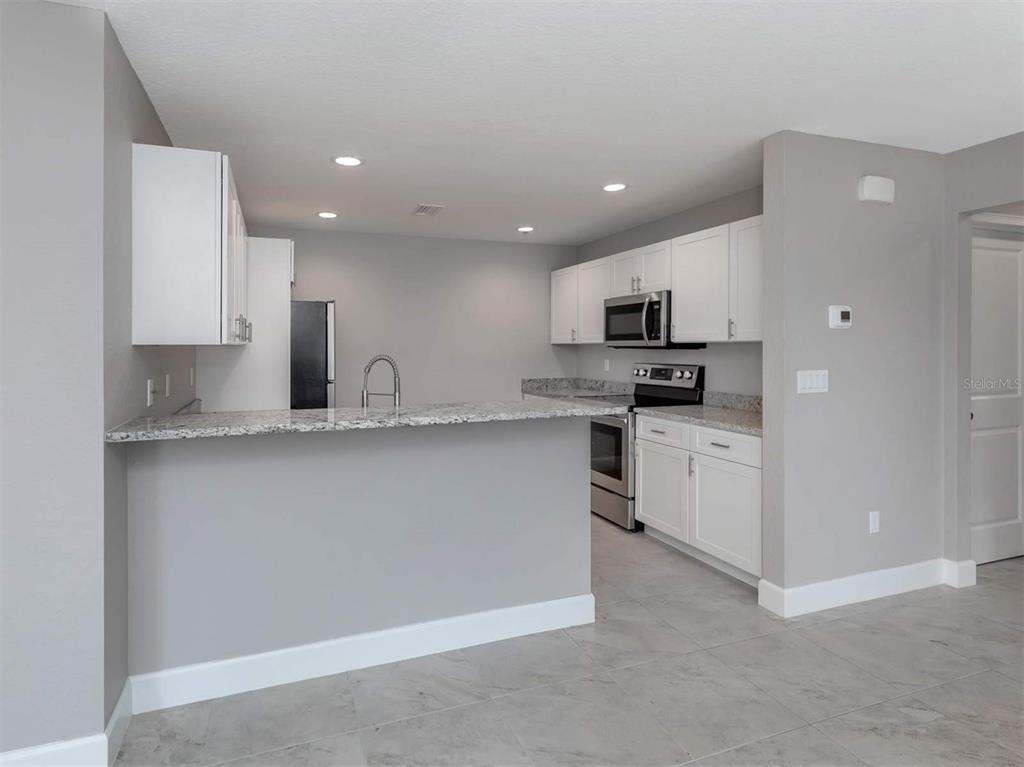 125 Boundary Boulevard, Unit 2 Rotonda West, FL 33947 - Photo 8 of 32 a kitchen with granite countertop a sink stainless steel appliances and white cabinets