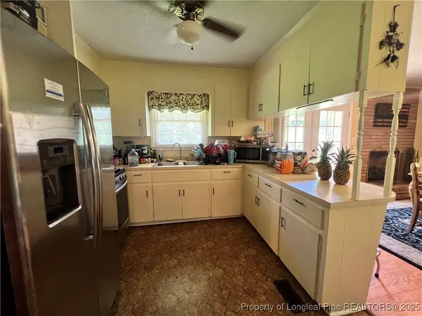 a kitchen with a sink stainless steel appliances cabinets and a window