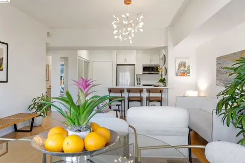a kitchen with stainless steel appliances granite countertop a sink a stove a chimney a dining table and chairs