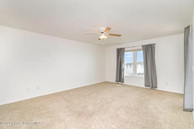 a view of an empty room with a ceiling fan
