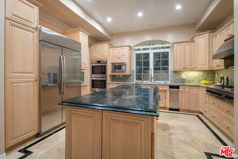 a kitchen with stainless steel appliances granite countertop a refrigerator a stove and a sink with wooden floor
