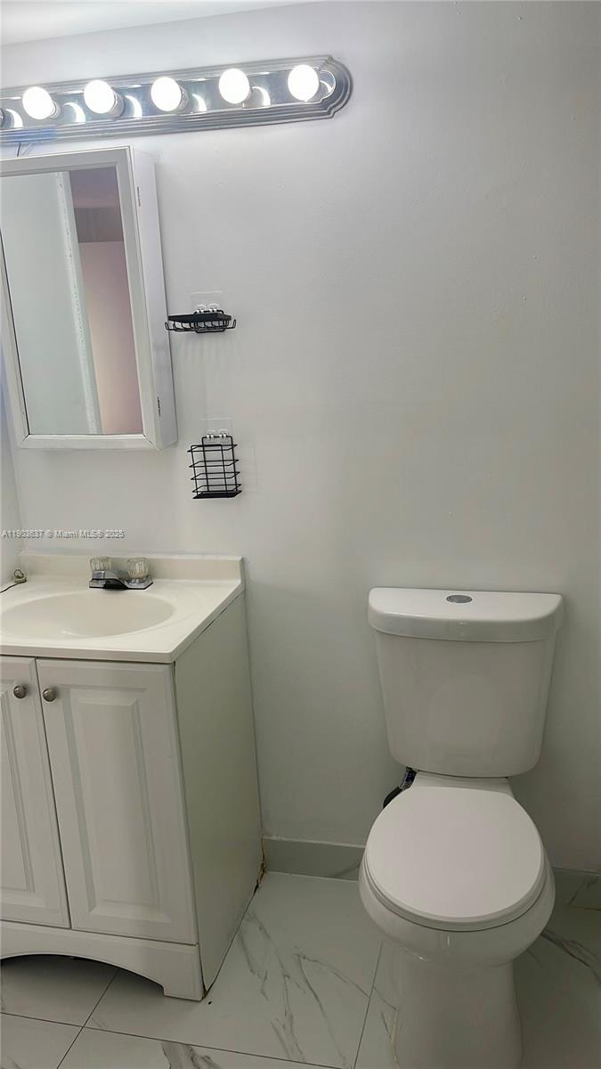 4801 Northwest 7th Street, Unit 70316 Miami, FL 33126 - Photo 6 of 9 a bathroom with a toilet sink and mirror