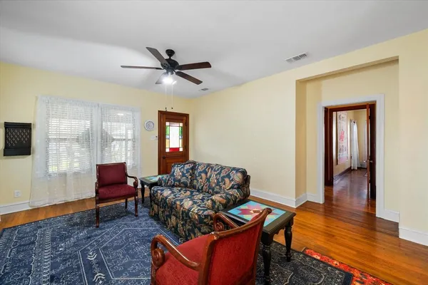 a view of a hallway with wooden floor and a bathroom