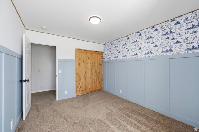 3732 Campbell Road Tooele, UT 84074 - Photo 39 of 69 Spacious room featuring board and batten wainscoting, patterned wallpaper, and a natural wood-finish barn door