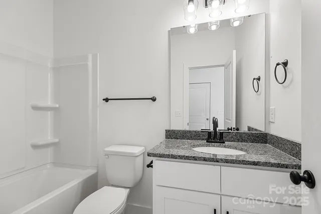 a bathroom with a granite countertop sink toilet and a mirror