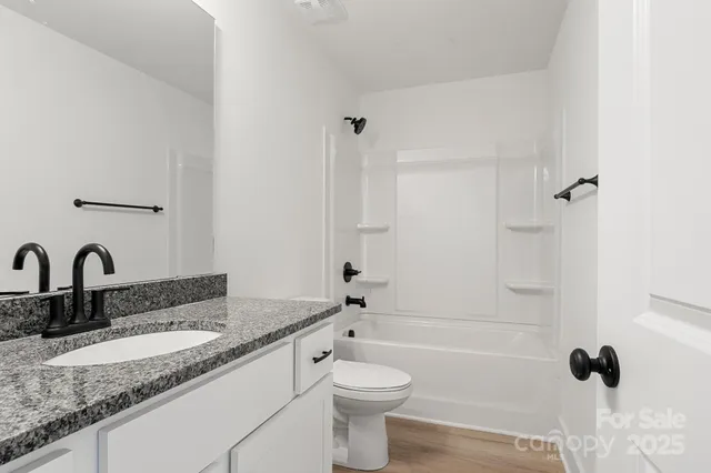 a bathroom with a granite countertop sink and a toilet