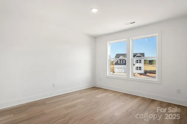 an empty room with wooden floor and window