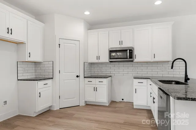 a kitchen with granite countertop white cabinets and stainless steel appliances