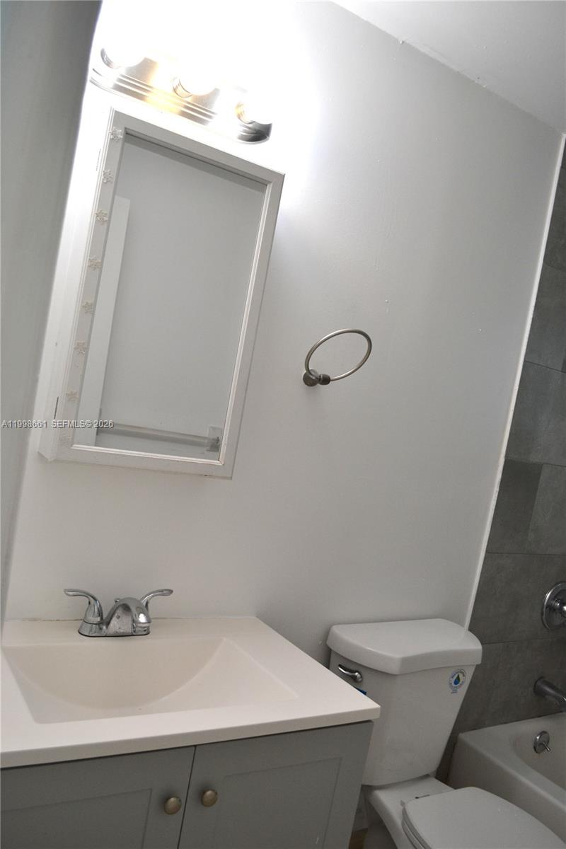 1037 Southwest 4th Street, Unit 4 Miami, FL 33130 - Photo 9 of 12 a bathroom with a sink and mirror with toilet