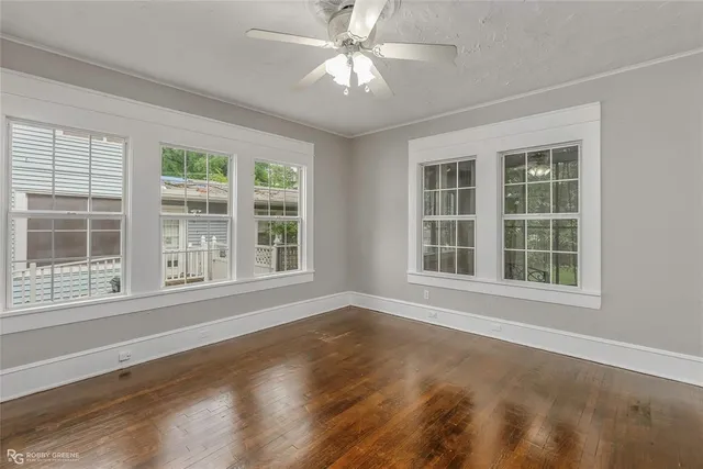 a view of an empty room with a window and wooden floor