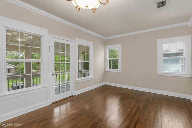 a view of an empty room with wooden floor and windows