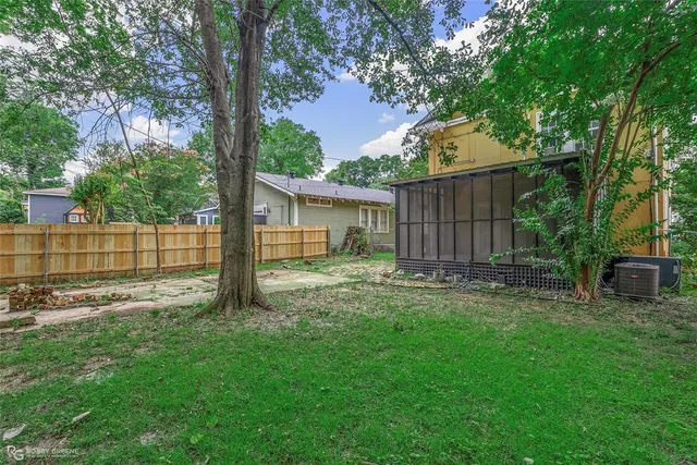 a view of a house with a yard and a large tree