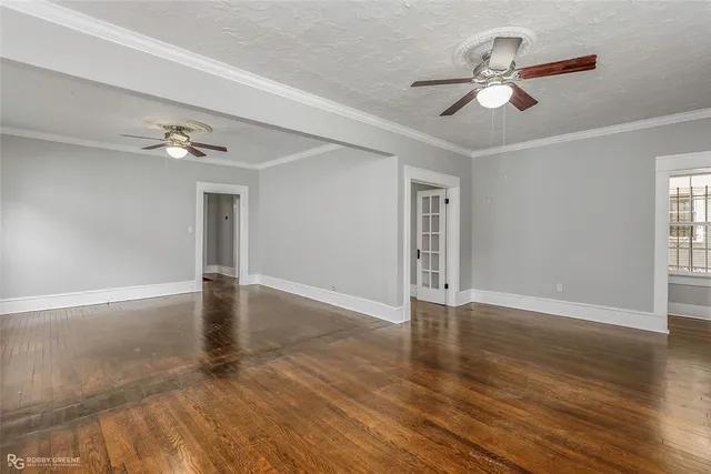a view of an empty room with wooden floor and a ceiling fan