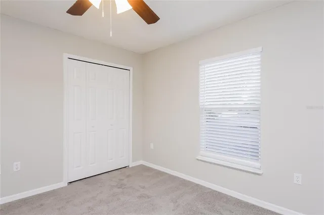 an empty room with a window and a ceiling fan