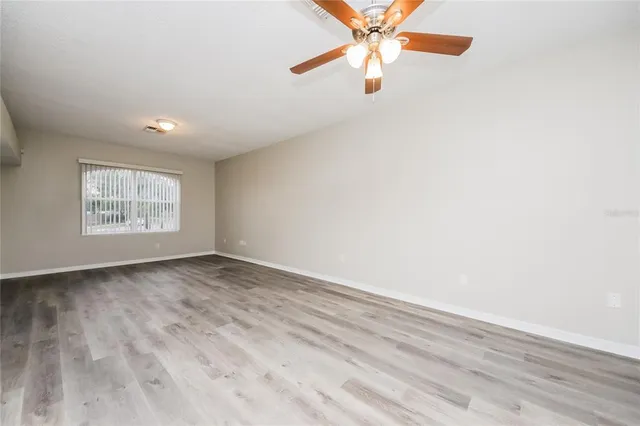 an empty room with windows and fan