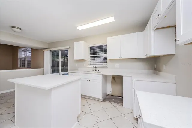 a kitchen with a sink a stove top oven and white cabinets