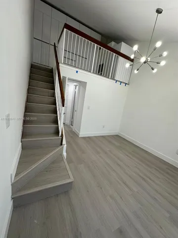 a view of staircase with railing and white walls