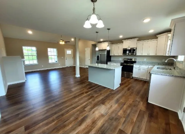 an open kitchen with wooden floor and stainless steel appliances