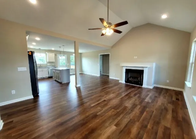 an empty room with wooden floor fireplace and windows