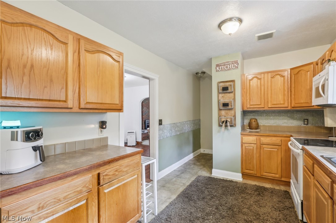 2998 Massillon Road Akron, OH 44312 - Photo 12 of 36 Kitchen with white appliances, tile floors, and tasteful backsplash