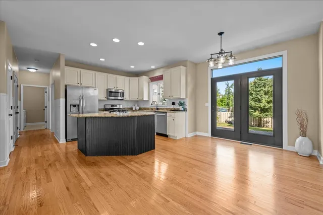 a kitchen with stainless steel appliances granite countertop a refrigerator a stove top oven a sink dishwasher and white cabinets with wooden floor