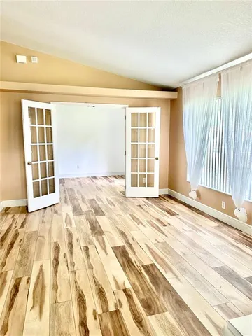 a view of an empty room with wooden floor and a window