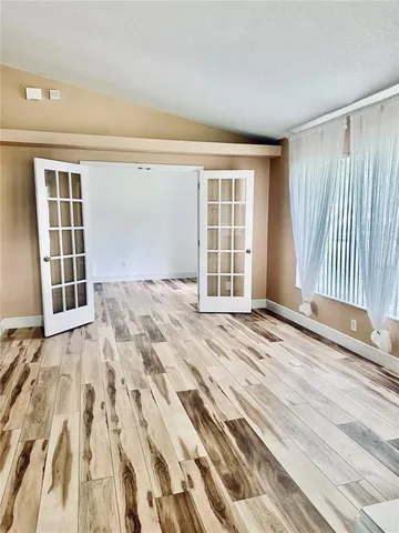 a view of an empty room with wooden floor and a window